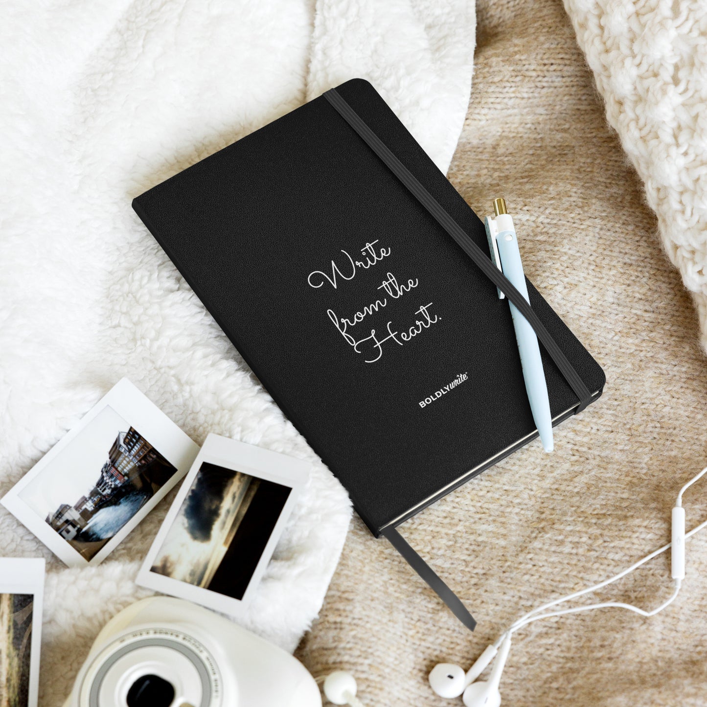 Write from the Heart black hardcover journal with pen, Polaroid photos, and earphones on a cozy cream blanket – Boldly Write